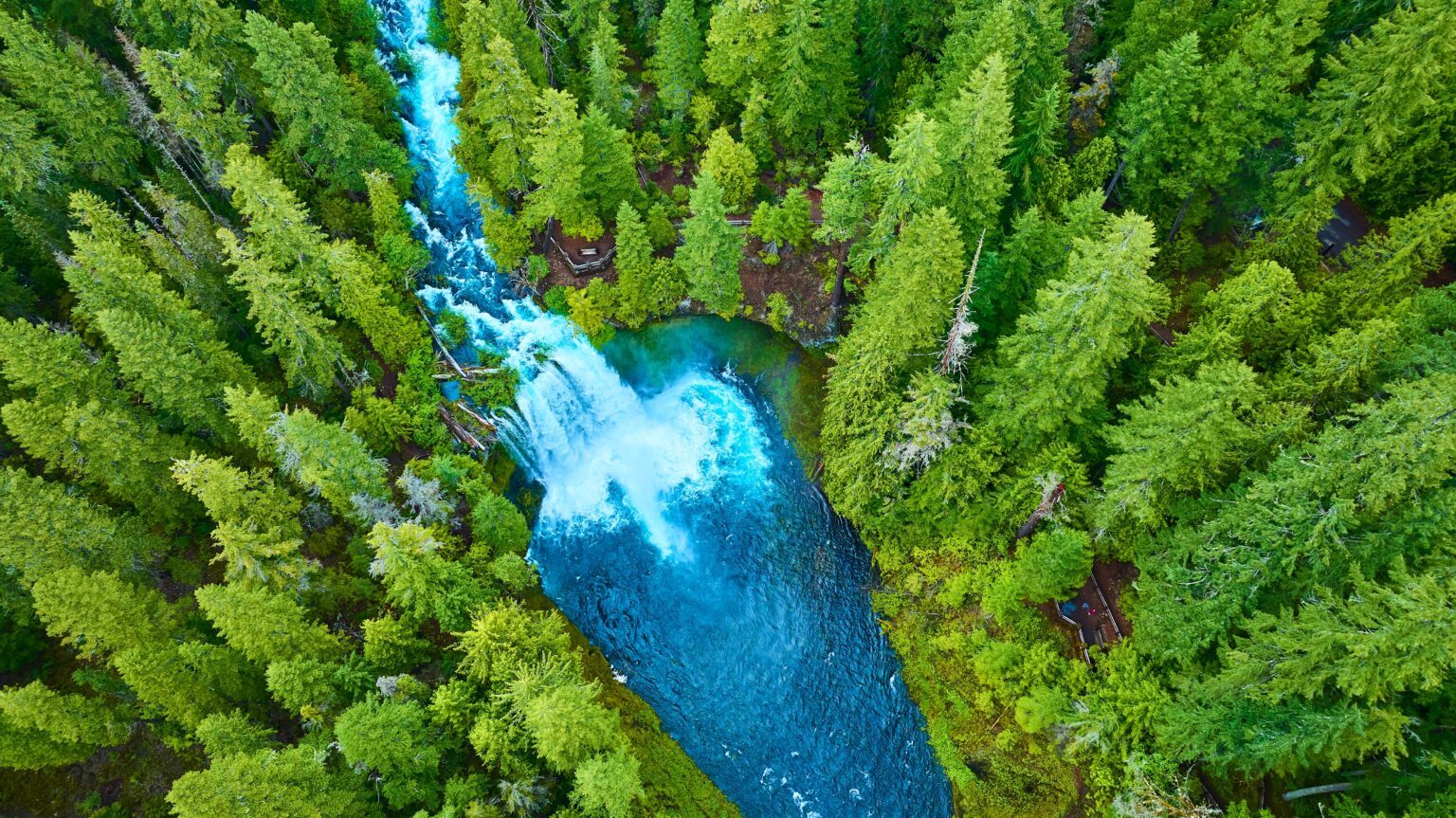 Aerial,View,Of,Turquoise,River,And,Waterfalls,Through,Lush,Forest